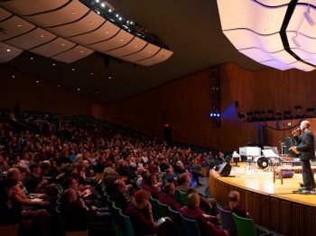 A man speaks on stage in front of a large audience.