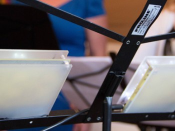 A music stand with two small white electronic devices.