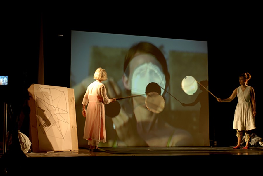 Two performers on a stage with an image projected in the background.